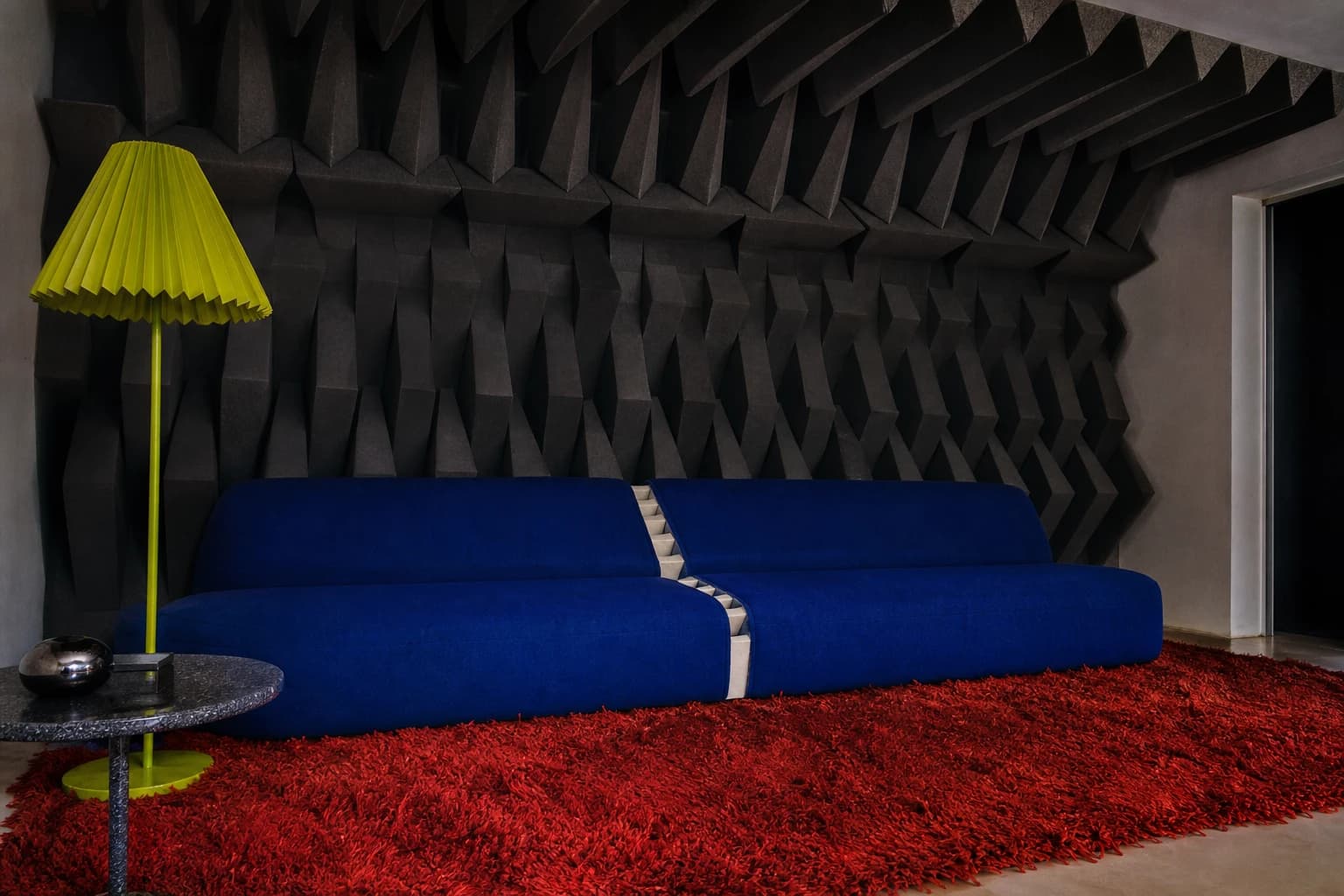 A cobalt sofa in a domestic living room lined with toothlike acoustic foam